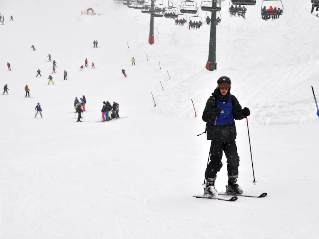 Person fährt auf die Kamera zu, dahinter die Piste.